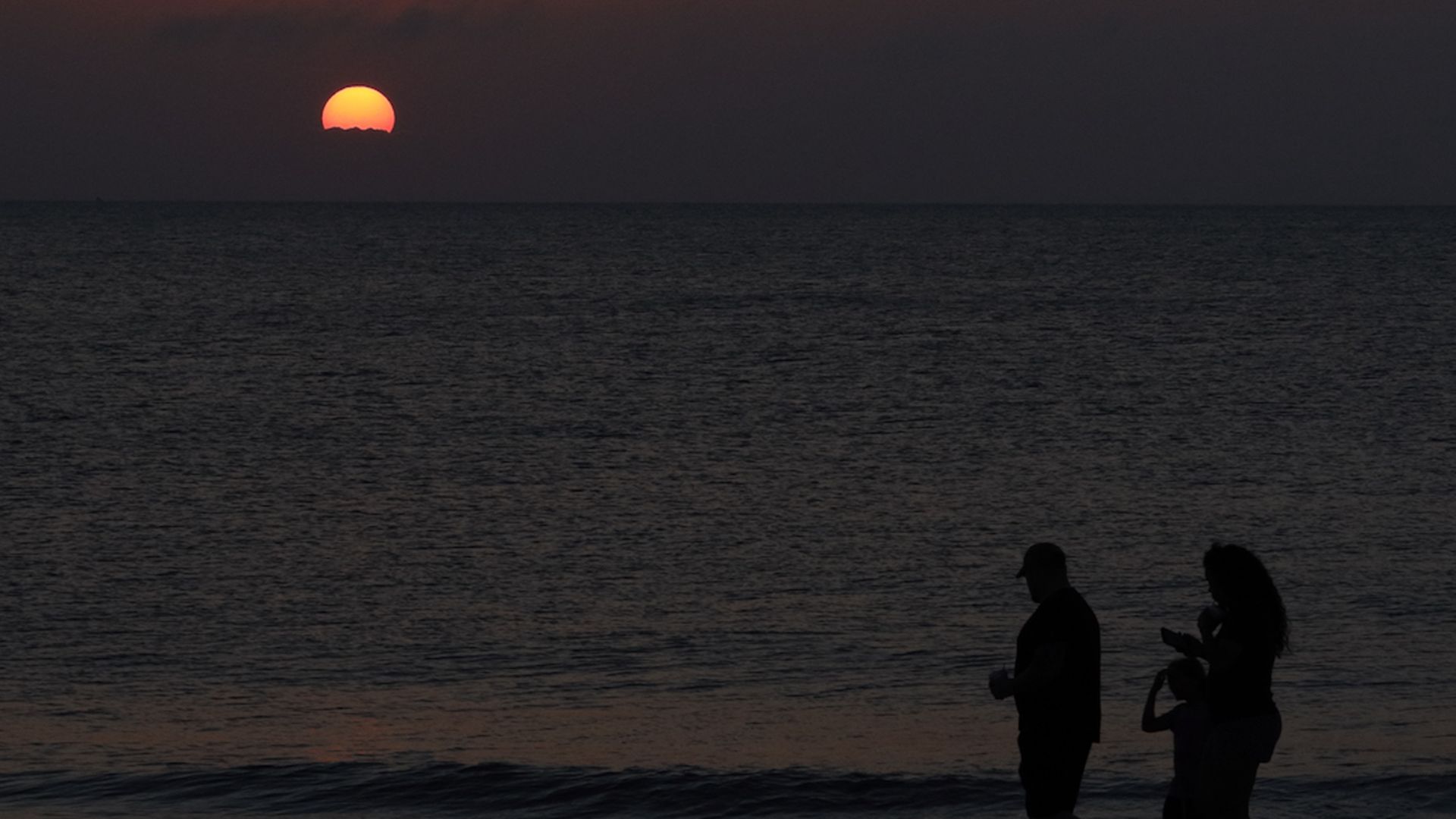 A family walking along the beach at sunset in St. Augustine, Florida